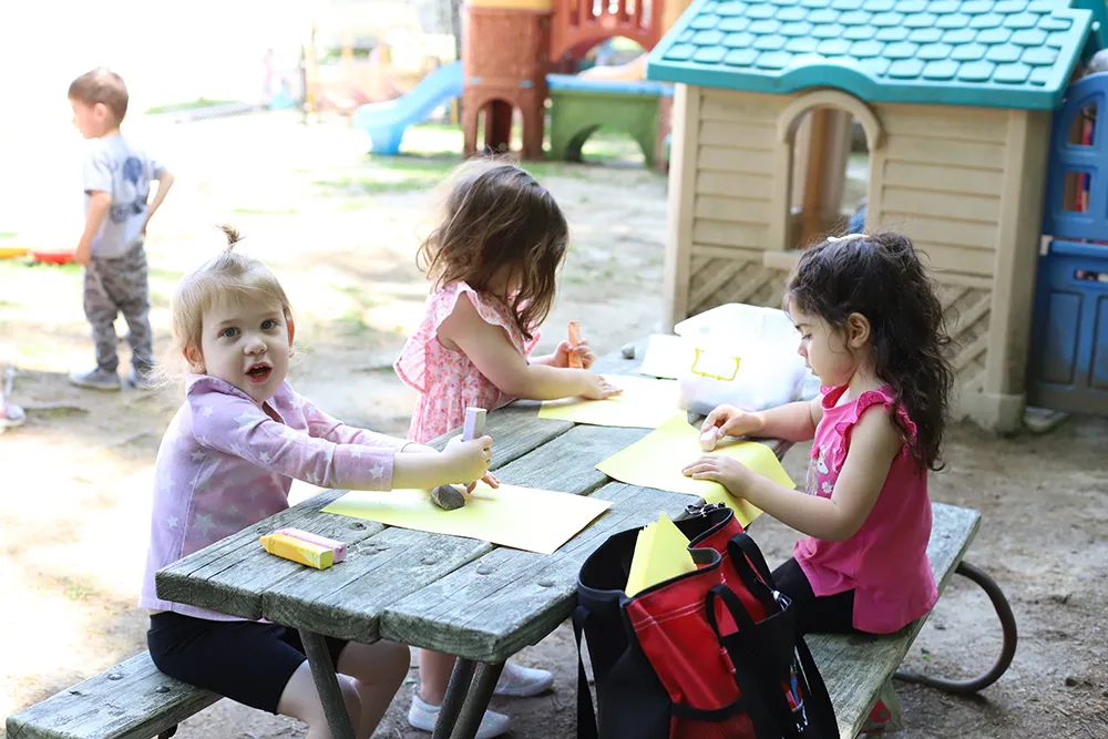 young girls drawing at a picnic table